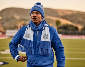 May include: A blue and white knit beanie with a pom-pom, a matching scarf, and a blue jacket. The scarf has white panels with the text "YOUR DESIGN HERE". The jacket has white cuffs and a white stripe on the sleeves.