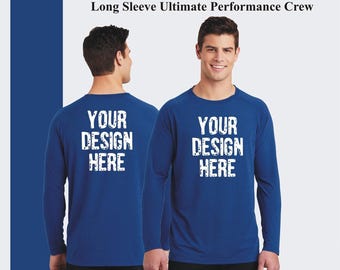 May include: A royal blue long-sleeve performance crew neck t-shirt with the text "YOUR DESIGN HERE" printed in white on the front and back.