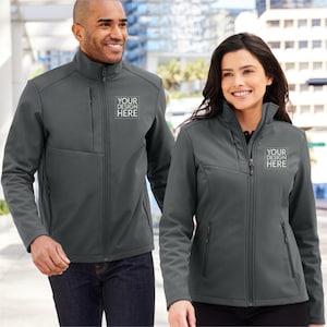 May include: Two people wearing gray softshell jackets with zipper closures. The jackets have a zippered pocket on the left chest with the text "YOUR DESIGN HERE" embroidered on it.