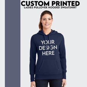 Peut inclure: Un sweat à capuche bleu marine avec une poche blanche et le texte "YOUR DESIGN HERE" imprimé sur le devant.