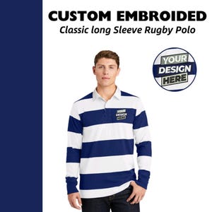 May include: A white and navy blue striped long-sleeve rugby polo shirt with a button-up collar. The shirt has a small embroidered patch on the chest that says "YOUR DESIGN HERE".