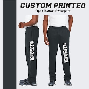 Peut inclure: Pantalon de survêtement noir à bas ouvert avec le texte "YOUR DESIGN HERE" imprimé sur le côté.