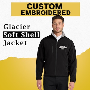 May include: Black Glacier Soft Shell Jacket with the text "CUSTOM EMBROIDERED" above. The jacket has a gray collar and a white shirt underneath. The text "CUSTOM EMBROIDERY HERE" is on the right chest.