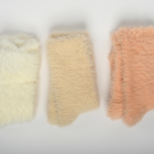 Puede incluir: Tres pares de calcetines peludos en diferentes tonos de rosa, beige y blanco.