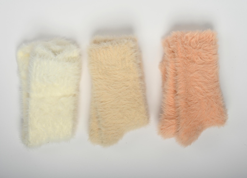 Puede incluir: Tres pares de calcetines peludos en diferentes tonos de rosa, beige y blanco.