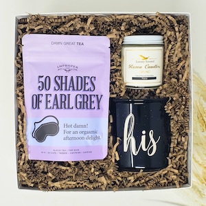 Peut inclure: Coffret cadeau avec un sachet de thé "50 Shades of Earl Grey", une tasse noire avec "his" en écriture blanche et une bougie parfumée. Le sachet de thé est lavande avec du texte noir et un masque de sommeil. La bougie a une étiquette dorée.