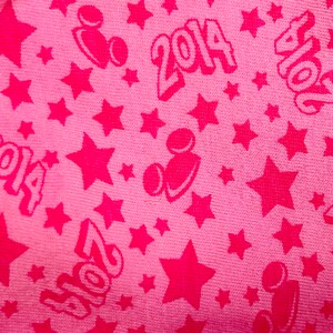 K&ouml;nnte beinhalten: Rosafarbener Stoff mit einem sich wiederholenden Muster aus Sternen, Mickey-Maus-K&ouml;pfen und dem Jahr 2014.