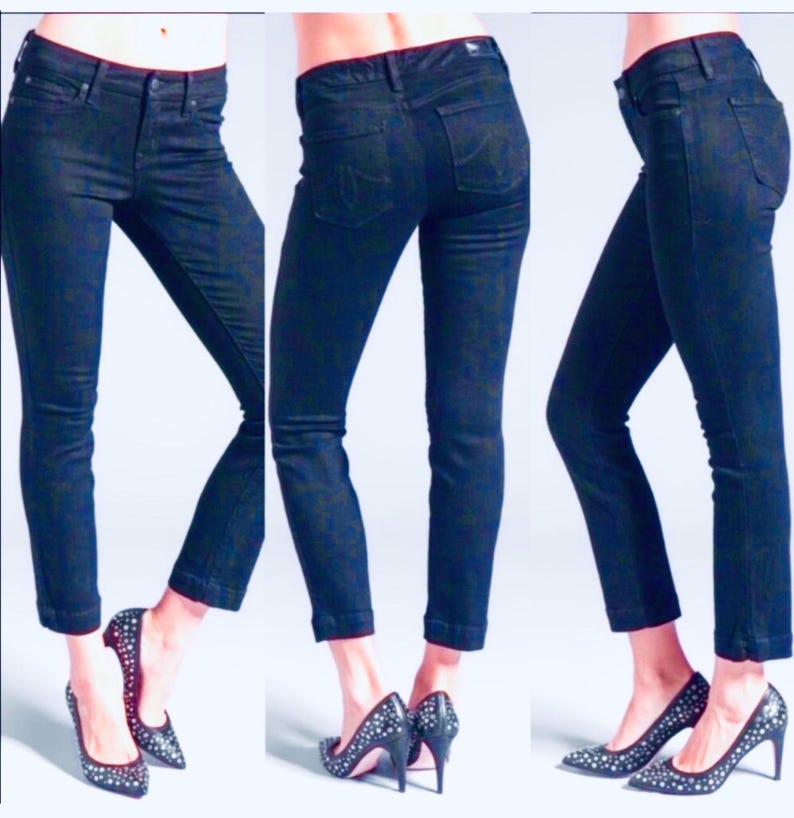 May include: Three views of dark wash denim jeans. The jeans have a slim fit, with a classic five-pocket design. The jeans are paired with black high-heeled shoes with silver embellishments.
