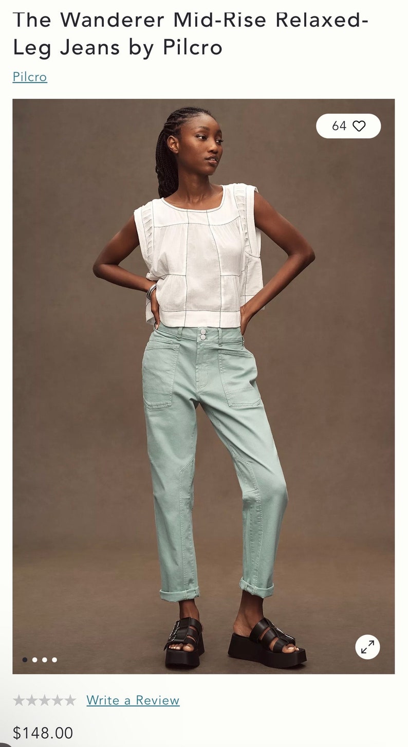 Puede incluir: Una mujer modela unos vaqueros relajados de talle medio en color verde claro. Los vaqueros tienen el bajo vuelto y se combinan con una camiseta blanca y sandalias negras. La camiseta tiene un escote cuadrado y un patr&oacute;n de rejilla.