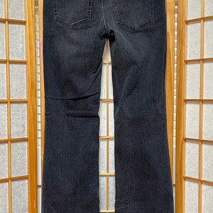 May include: A pair of black flared jeans with a wide leg opening. The jeans have a classic five-pocket design and a zipper fly.
