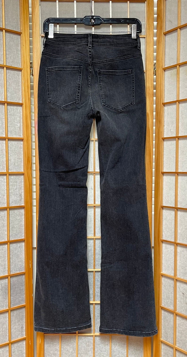 May include: A pair of black flared jeans with a wide leg opening. The jeans have a classic five-pocket design and a zipper fly.