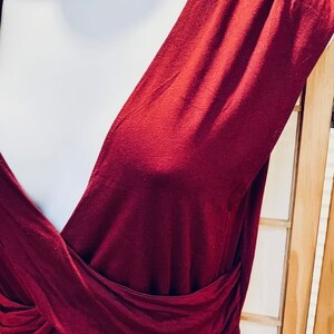 Pu&ograve; includere: Un abito bordeaux senza maniche con scollo a V profondo e un corpetto avvolgente.
