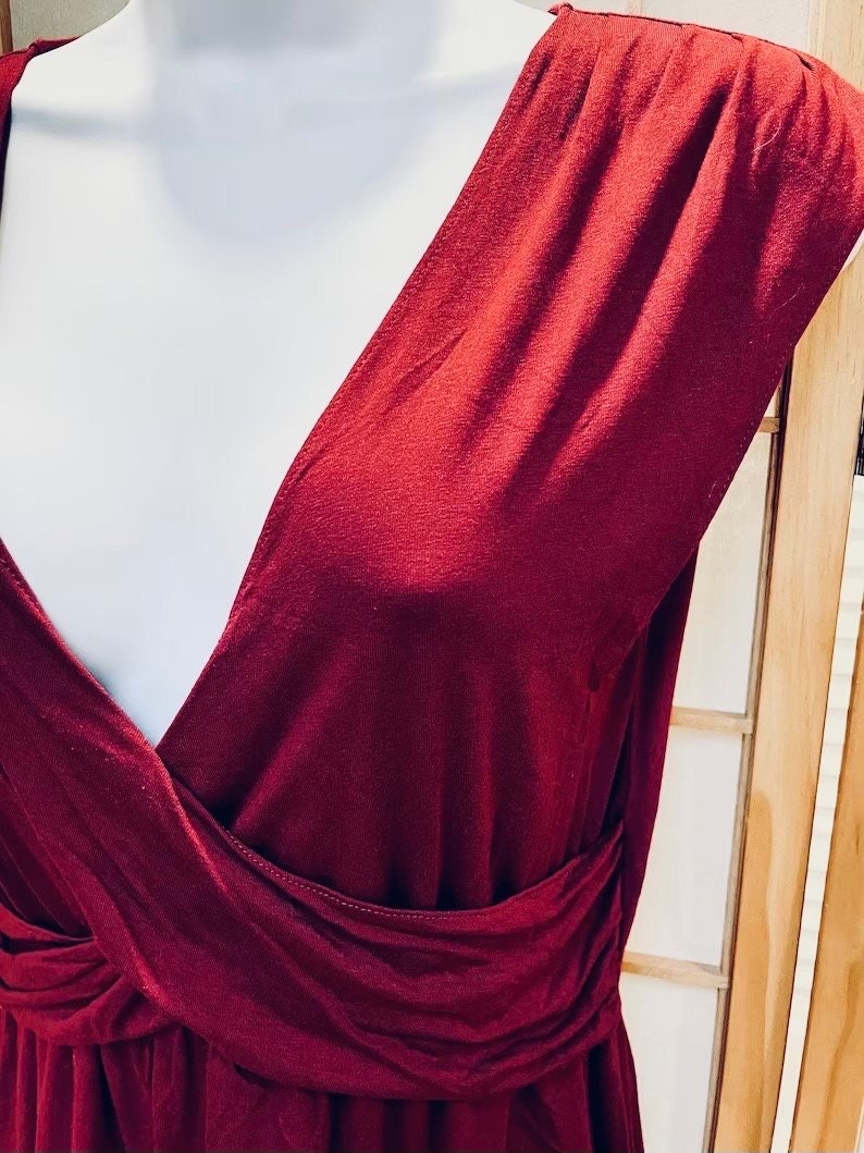 Pu&ograve; includere: Un abito bordeaux senza maniche con scollo a V profondo e un corpetto avvolgente.
