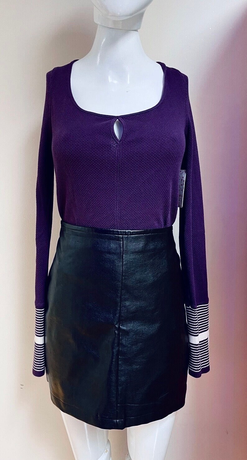 May include: A purple long-sleeved shirt with a keyhole neckline and white stripes on the cuffs, paired with a black leather mini skirt.