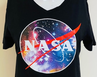 Camiseta vintage oficial de la NASA con el logo grande de los 90. Color negro. Estampado colorido de astronautas de la NASA, espacio, universo cósmico, estrellas y galaxias. Talla L.