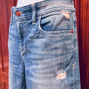 K&ouml;nnte beinhalten: Hellblaue Jeans aus Denim mit Destroyed-Effekt, einer einzigen Tasche vorne und einem braunen Knopf. Die Jeans werden an einem Mannequin getragen.