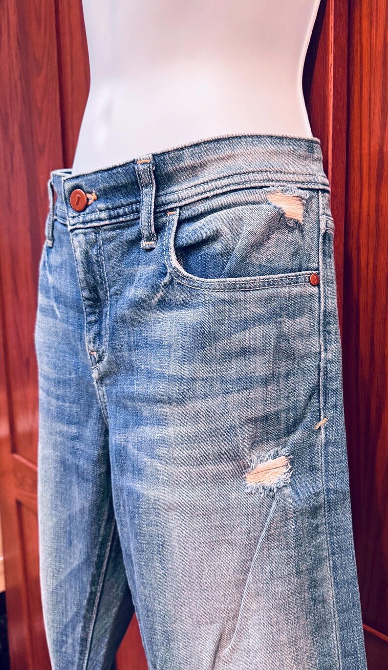 K&ouml;nnte beinhalten: Hellblaue Jeans aus Denim mit Destroyed-Effekt, einer einzigen Tasche vorne und einem braunen Knopf. Die Jeans werden an einem Mannequin getragen.