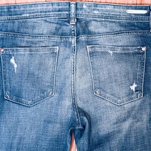 K&ouml;nnte beinhalten: Eine blaue Jeans mit Destroyed-Details und zwei Ges&auml;&szlig;taschen.
