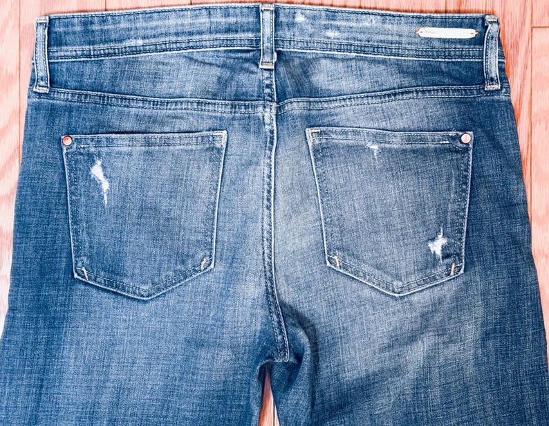 K&ouml;nnte beinhalten: Eine blaue Jeans mit Destroyed-Details und zwei Ges&auml;&szlig;taschen.