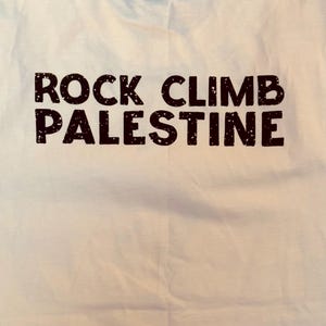 Puede incluir: Camiseta blanca con texto negro que dice "ROCK CLIMB PALESTINE".