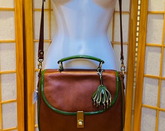 Bolso de mano Pilcro de piel marrón caoba con ribetes en verde esmeralda, bandolera con asa superior y correa larga extraíble.
