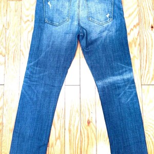 K&ouml;nnte beinhalten: Eine blaue Jeans mit Destroyed-Details. Die Jeans hat eine gerade Passform und eine helle Waschung.