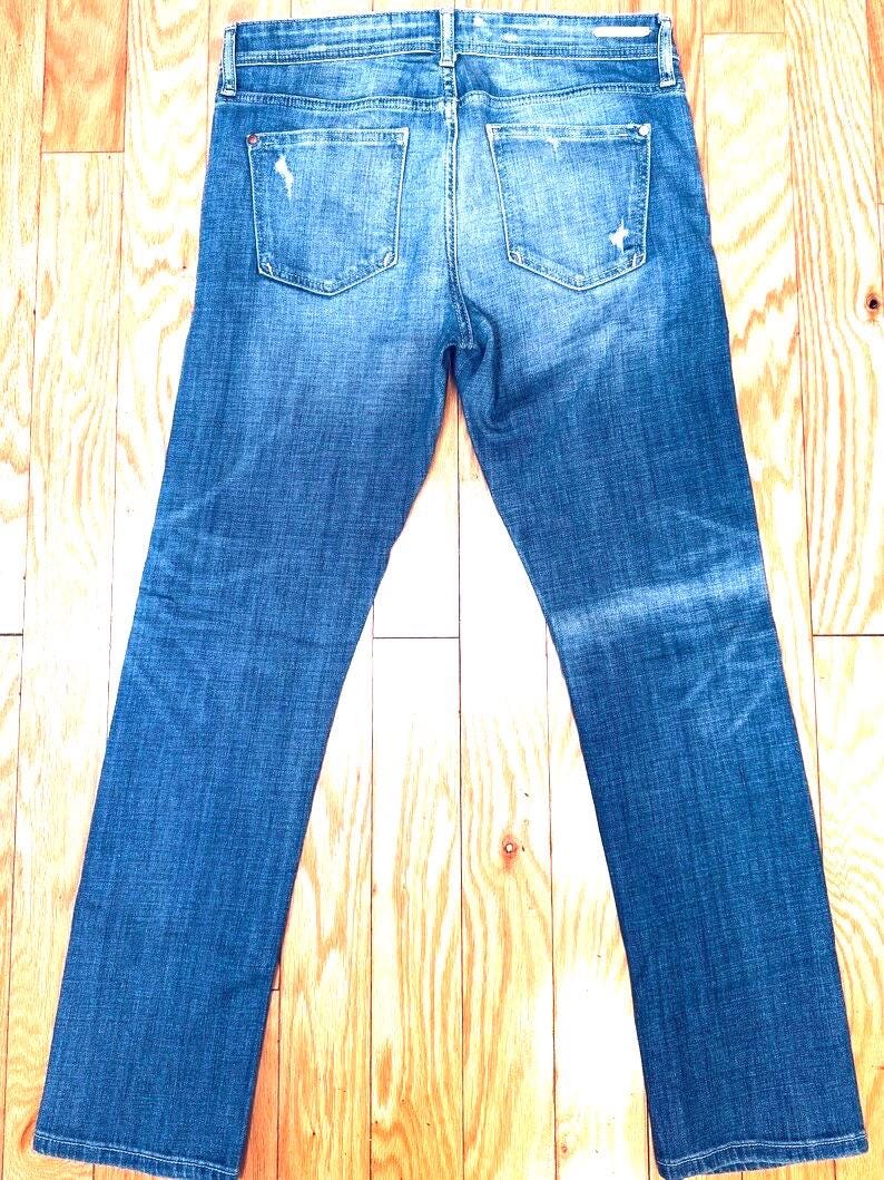 K&ouml;nnte beinhalten: Eine blaue Jeans mit Destroyed-Details. Die Jeans hat eine gerade Passform und eine helle Waschung.