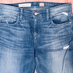 K&ouml;nnte beinhalten: Eine blaue Jeans mit Destroyed-Look. Die Jeans hat eine helle Waschung und eine gerade Passform. Die Jeans hat einen kleinen Riss am rechten Bein.