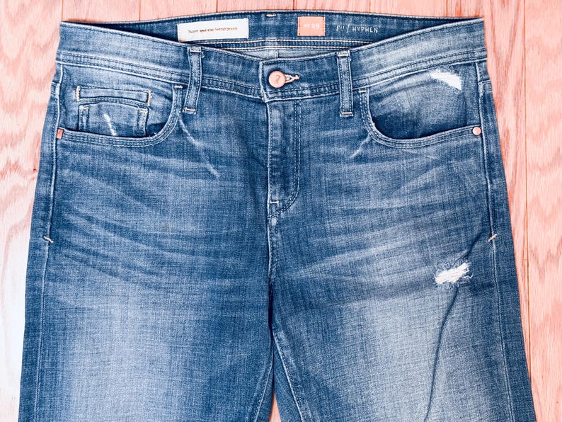 K&ouml;nnte beinhalten: Eine blaue Jeans mit Destroyed-Look. Die Jeans hat eine helle Waschung und eine gerade Passform. Die Jeans hat einen kleinen Riss am rechten Bein.