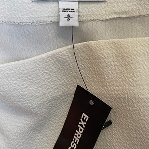 May include: White clothing tag with black text that reads "EXPRESS" and "MADE IN VIETNAM". The tag also has a size label that reads "S" and "P".