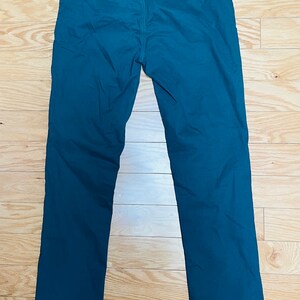Puede incluir: Pantalones de color verde azulado con dise&ntilde;o de pierna recta. La parte trasera muestra los bolsillos y la cintura. Los pantalones est&aacute;n hechos de una tela de color liso y parecen ser de estilo casual. La longitud del pantal&oacute;n es de unos 100 cm.