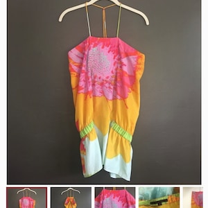 May include: A sleeveless halter top with a colorful abstract print in shades of pink, orange, and yellow. The top has a green elastic band at the bottom.