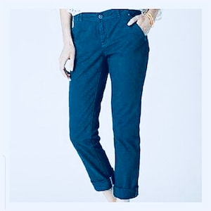 Puede incluir: Pantalones de color verde azulado oscuro con cierre de bot&oacute;n y bolsillos. Los pantalones tienen una pernera recta y est&aacute;n doblados en los tobillos. La tela es lisa y de color s&oacute;lido.