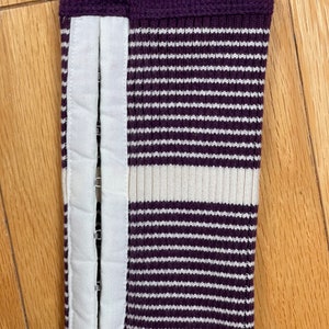 May include: Purple and white striped sweater cuff with a white fabric panel and metal poppers.
