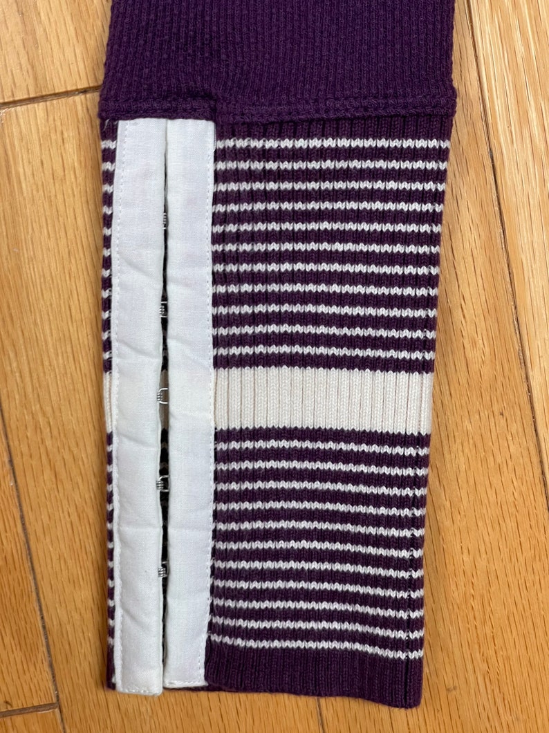 May include: Purple and white striped sweater cuff with a white fabric panel and metal poppers.