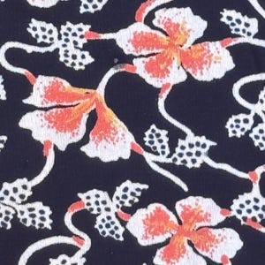 May include: Close-up of a fabric with a repeating floral pattern. The design features white and orange flowers with delicate stems and dotted leaf clusters against a dark navy blue background. The overall aesthetic is reminiscent of a vintage textile.