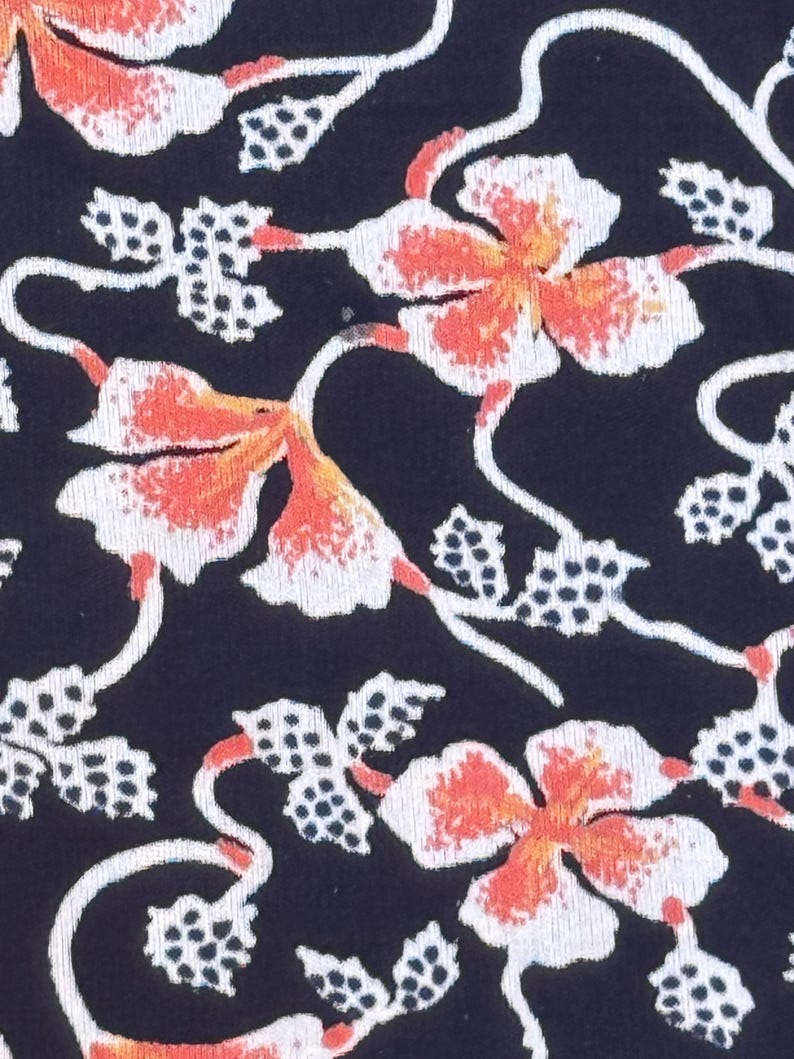 May include: Close-up of a fabric with a repeating floral pattern. The design features white and orange flowers with delicate stems and dotted leaf clusters against a dark navy blue background. The overall aesthetic is reminiscent of a vintage textile.