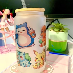 Op de afbeelding: Een matglazen beker met een bamboe deksel en een rietje. De beker heeft een ontwerp met verschillende Pokémon-personages die Starbucks-bekers vasthouden. De personages zijn onder andere Squirtle, Charmander, Bulbasaur en Pikachu.
