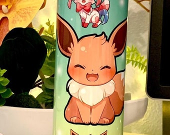 May include: A stainless steel tumbler with a teal background and three different Pokemon characters. The characters are Eevee, Flareon, and Sylveon. The tumbler has a shiny, sparkly finish.