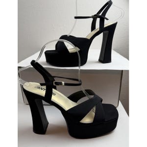 May include: Black platform sandals with a chunky heel and ankle strap. The sandals feature a criss-cross strap design over the toes and a buckle fastening. The brand name "PANTO" is visible on the insole.