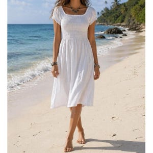 May include: A white midi dress featuring a smocked bodice, short puff sleeves, and a square neckline. The dress has a fitted upper section that transitions into a loose, flowing skirt that falls below the knees, crafted from a solid white fabric.