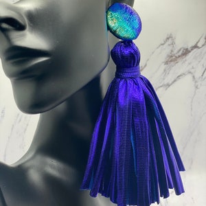 May include: A pair of large, statement earrings with a blue tassel and a round, iridescent green and blue top.