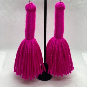 May include: A pair of long, pink tassel earrings. The tassels are made of yarn and are about 3 inches long.