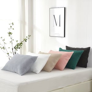 May include: Five pillowcases in different colors, including gray, white, beige, pink, and green, are arranged on a white bed. The pillowcases are made of a soft, textured fabric.
