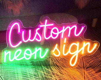 May include: Custom neon sign with the words "Custom neon sign" in a pink, green, and white neon font.