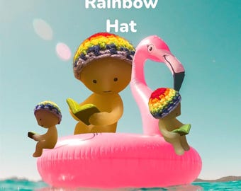 Könnte beinhalten: Das Bild zeigt den Text "Rainbow Hat" über drei gelben Figuren, die Regenbogen-Häkelhüte tragen. Eine Figur liest ein Buch, während sie auf einem rosa Flamingo-Schwimmring im Wasser schwimmt.