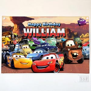 May include: A banner featuring the text "Happy Birthday WILLIAM" with a background of cartoon cars. The banner includes images of various animated cars, including Lightning McQueen and Mater, set against a desert landscape.