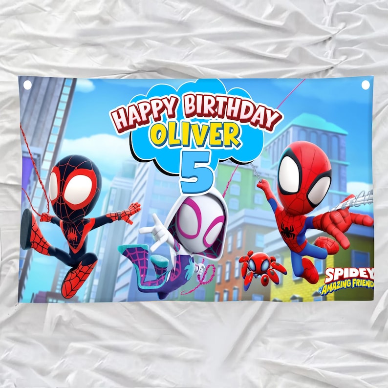 May include: A rectangular birthday banner featuring the text Happy Birthday Oliver 5 in a blue cloud shape. The design includes three animated spider characters in red, black, and white suits, and a small red spider, set against a city background.