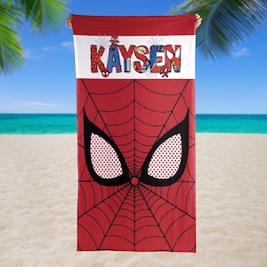 May include: Red beach towel featuring a Spider-Man design. The towel has a red spiderweb pattern with large black eyes and a white dotted pattern. The name "Kaysen" is printed in colorful letters across the top.