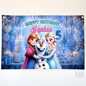 May include: A birthday banner featuring characters from the movie Frozen, with the text "Happy Birthday Sophia 5". The banner has a blue and white color scheme with images of a birthday cake, balloons, and snowflakes.
